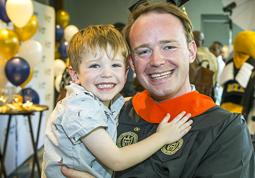 man holding child at graduation event